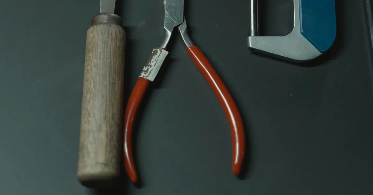 Deburring PEEK parts needs hand tools: a file, pliers and a micrometer laid out on a dark surface