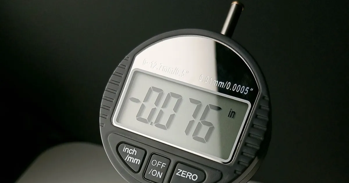 Inspecting PEEK parts with a digital thickness gauge held in a hand, display reading 0.076 inch
