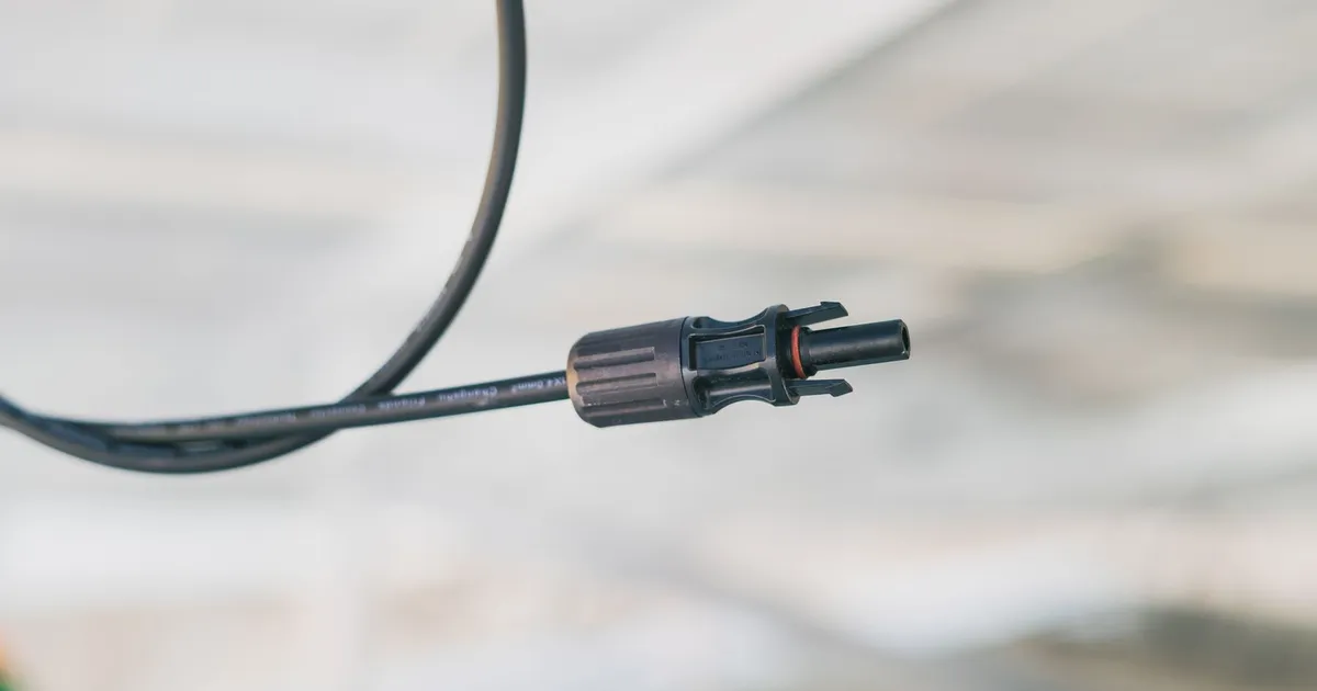 PEEK connector insulator context: a black electrical cable connector with a locking sleeve on a cable against a blurred background