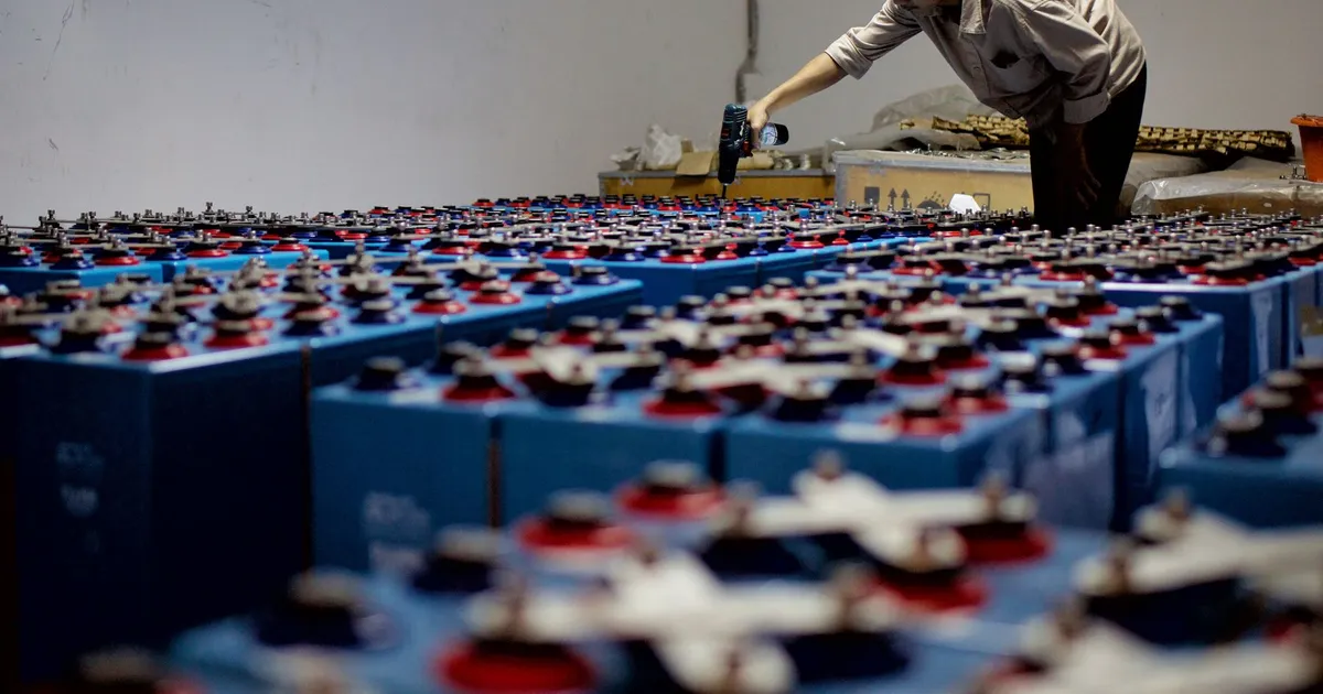 PEEK EV battery equipment context: rows of blue industrial batteries in a warehouse with a worker bending over them in the background