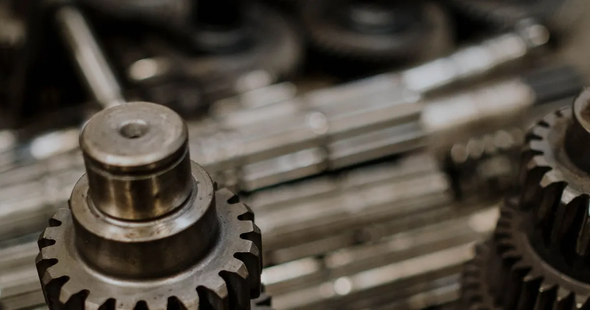 PEEK gears and thrust washers context: stacked metal gears with cut teeth on shafts in a workshop