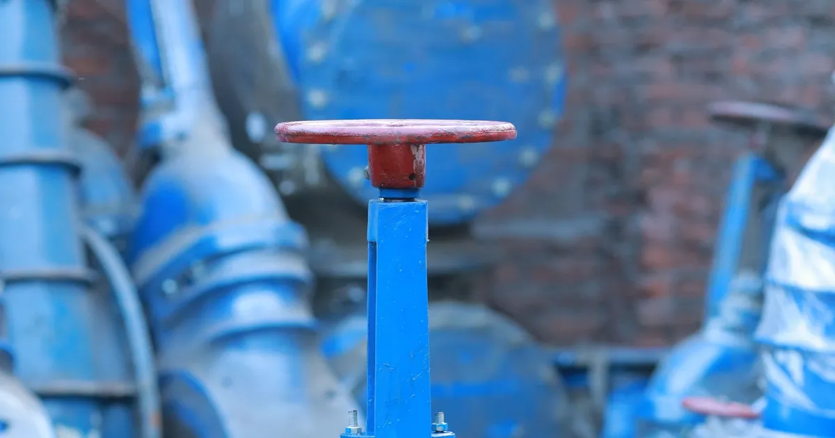 PEEK vs PPS for valve parts: a blue industrial gate valve with a rising stem standing in a warehouse