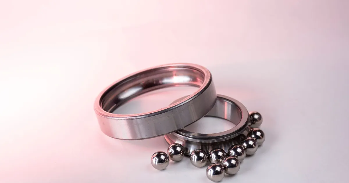 PEEK wear rings context: a polished metal ring and a bearing race with steel balls on a white surface