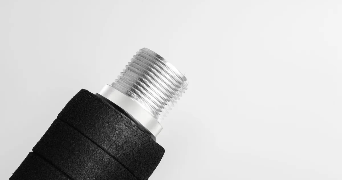 Threading PEEK parts: a male threaded metal fitting on a black handle shown against a white background
